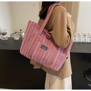 Détail du sac cabas en velours côtelé à rayures roses et noires porté par un mannequin