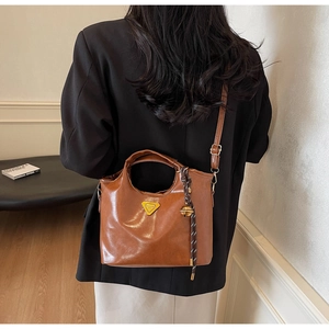 Detailansicht braune Vintage Handtasche mit goldenem Dreieck und Anhänger aus Leder
