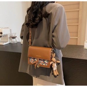 Close-up of vintage brown crossbody bag featuring woven texture and cute bunny charm