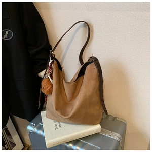 Grand sac cabas marron en cuir mat avec breloque ours et foulard sur une valise