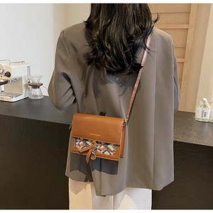 Detail of vintage caramel crossbody bag with woven flap, metal ring and tassel charm