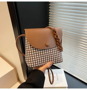 Detail of vintage crossbody bag with houndstooth fabric and brown leather stitching
