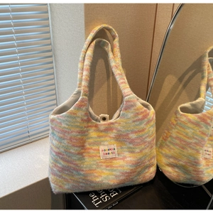 Detail of multi-color woven tote bag with metallic snap button and square logo patch