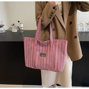 Détail du sac cabas en velours côtelé rayé rose et noir montrant la texture et l'écusson mode