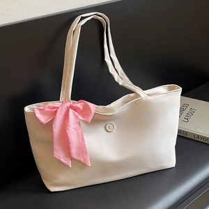 Schicke beige Satintasche mit rosa Karoschleife und 'E'-Abzeichen für den Alltag