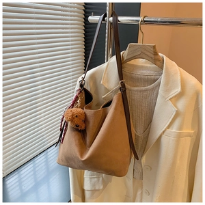 Détail d'un cabas en daim marron avec pendentif ours et foulard rayé décoratif