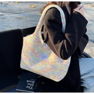 Detailed knit texture of colorful striped tote bag with brand label in outdoor setting