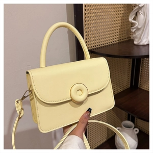 Detailed shot of cream PU leather handbag with circular buckle and adjustable strap