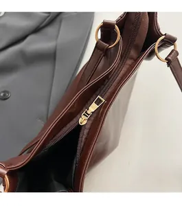 Macro view of smooth golden metal zipper and dark brown leather texture on tote bag