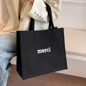 Borsa tote minimalista in tela nera da donna con scritta Merci bianca e manici lunghi