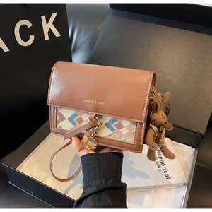 Detail of retro brown leather crossbody bag featuring geometric knit and rabbit charm