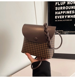Close-up of brown houndstooth mini bucket bag with leather handle and woven shoulder strap
