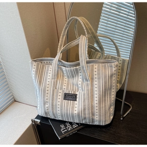 Détail de la texture d'un sac cabas en toile rayée avec un écusson de mode minimaliste