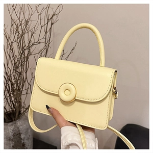 Detail of cream yellow crossbody bag featuring round button decor and smooth leather finish