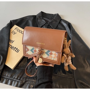Detail of vintage brown crossbody bag with woven texture and cute rabbit charm