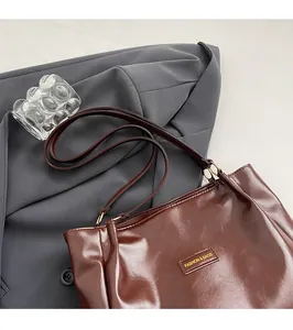 Detail of dark brown leather tote bag with thin straps on a grey suit background