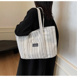 Détail d'un grand sac cabas en toile avec des rayures noires et une étiquette carrée tissée