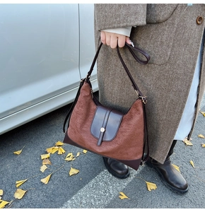 Detail showing the brown suede and leather texture of a large tote bag in autumn setting