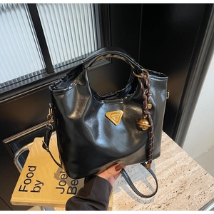 Nahaufnahme der schwarzen Lackleder-Handtasche mit goldenem dreieckigem Metall-Logo