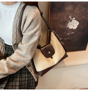Detailed side view of two-tone suede tote bag worn by a model in a cozy setting