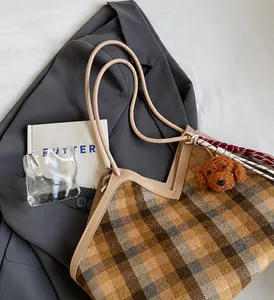Detail of checkered tweed tote bag featuring thin brown handles and cute bear charm