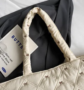 Détail du sac cabas matelassé avec broderie de nœuds et poignée rembourrée