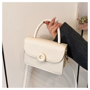 Close-up of a cream white PU leather handbag with round button closure and top handle