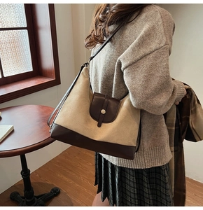 Detail view of large canvas tote bag with brown leather flap and vintage round buckle