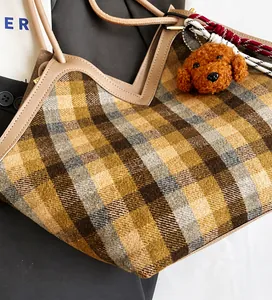 Close-up of retro plaid tote bag with khaki leather trim and brown plush puppy charm