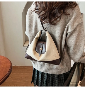 Detail of a color-block tote bag in beige fabric and brown leather with gold clasp