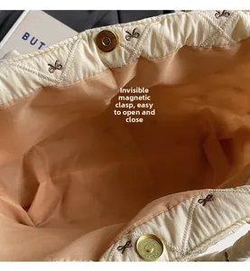 Détail du sac cabas matelassé avec fermeture magnétique et broderie de nœuds élégante