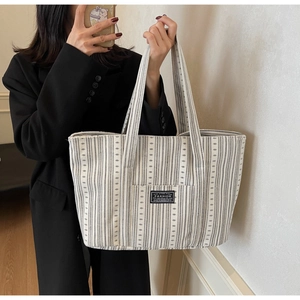 Détail du sac cabas en toile rayée avec étiquette mode porté par un mannequin