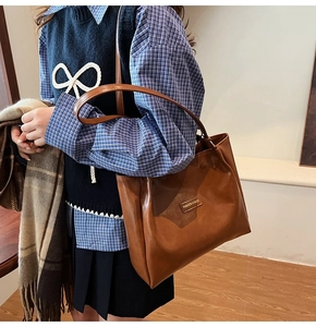 Detail of a brown leather tote bag with a rectangular fashion tag for stylish daily commute