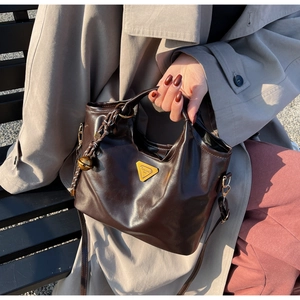 Detailaufnahme der dunkelbraunen Vintage-Handtasche mit goldenem Dreiecksbeschlag