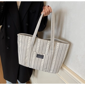 Détail du grand sac cabas en toile à rayures verticales et étiquette de mode devant