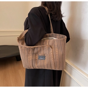 Détail de la texture du velours côtelé marron et de l'étiquette noire sur le sac cabas