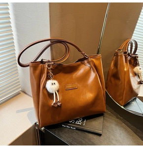Detailed view of caramel tote bag with plush monster charm and leather texture