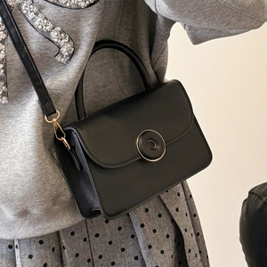 Classic black matte leather crossbody bag with golden circular magnetic buckle closure