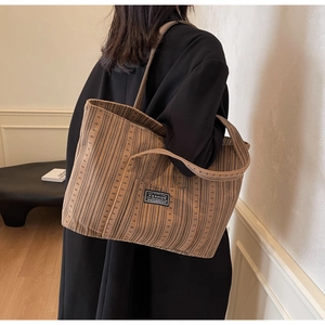 Vue détaillée d'un grand sac cabas rayé porté avec une tenue noire minimaliste