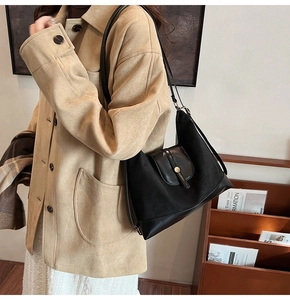 Detail view of the black tote bag featuring premium leather patchwork and metal buckle accent