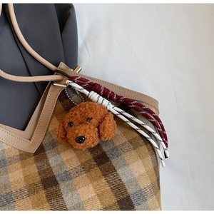 Detail of cute brown teddy dog plush pendant on a retro plaid canvas shoulder bag