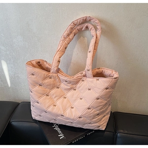 Close-up of light pink quilted tote bag with brown embroidered bows and soft cotton texture