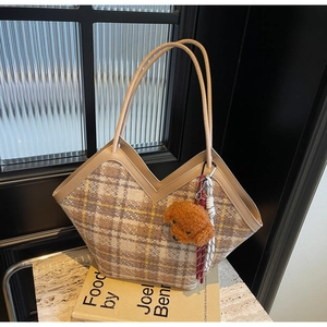Detail of checkered woolen tote bag featuring a V-shaped top and teddy bear charm