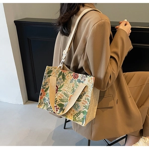 Floral embroidered linen tote bag shown on a model with adjustable crossbody strap
