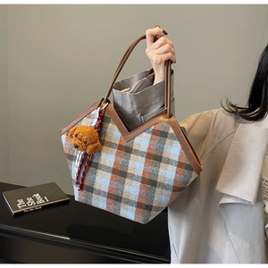 Detail of checkered tote bag featuring a V-shaped top, brown handles and dog plush charm