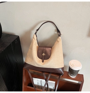 Detail of canvas and brown leather tote showing gold metal clasp and adjustable strap