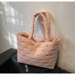 Detail of pink quilted tote bag featuring bow embroidery and spacious shoulder straps