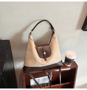 Detail view of large tote bag with beige canvas and dark brown leather accents and gold clasp