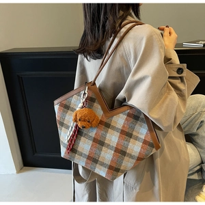 Detail shot of vintage plaid tote bag with teddy charm on a khaki trench coat