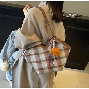 Detail of retro plaid tote bag with brown leather trim and cute plush dog charm